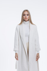 Fototapeta premium young fashionable beautiful girl in a trendy white coat posing on a white background