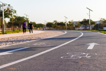 Obraz premium Jogging and cycling tracks in Al Warqa park, Dubai, UAE early in the morning. Lamp post powered by solar panels can be seen in the picture. Outdoors