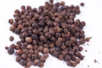 Black pepper. Heap of peppercorns isolated on white background.