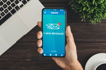 Woman Holding Phone With New E-Mail Message Sitting In Office