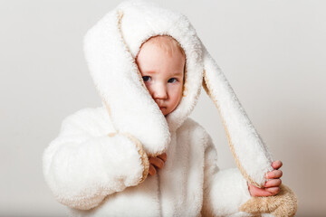 half-year-old European baby girl in fluffy white bunny costume on white background