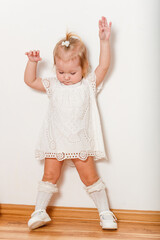 Cute half-old blonde girl in white dress and full-length golf cart poses