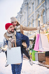 Joyful loving couple walking outdoors in snowy city