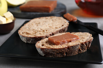 Bread with delicious quince paste on black plate, closeup