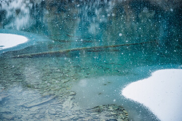 heavy snowfall over deep blue transparent mountain lake in Valais