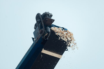 the sawdust conveyor works at a woodworking plant. production waste is dumped in a large pile. lumber remnants
