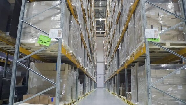 Front motion view of interior and shelves with boxes in modern warehouse. Shot of products on metal racks during working process in storage room of industrial factory. Concept: business, storehouse