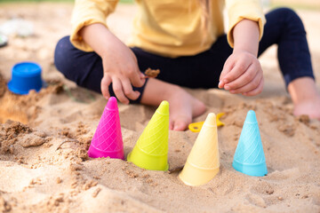 Different colors molds ice cream for sand. On background little cute child play with sand. Enjoy and play outdoors in summer. Great vacation with children. 