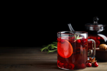 Tasty hot cranberry tea with rosemary and lemon on wooden table. Space for text