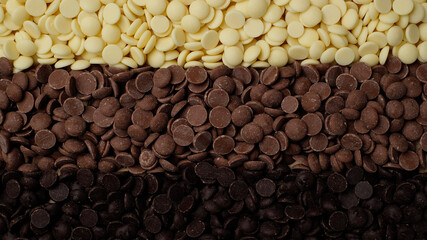chocolate chips from white, milk, black chocolate top view. confectionery concept