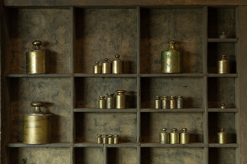 Fototapeta na wymiar Small vintage brass weights displayed in letterpress drawer. 