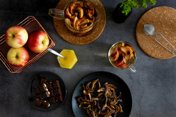 Composition of tea drinking. On a dark background, tea with dried fruits, apples, honey and chocolate. Antiviral kit. View from above 