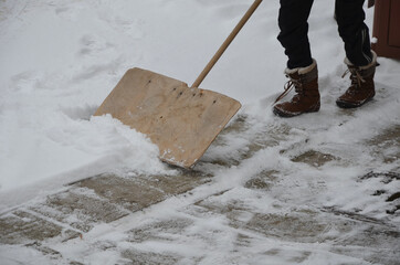 a snow disaster has covered places where snow is a rarity. girl clears the snow structure using the...