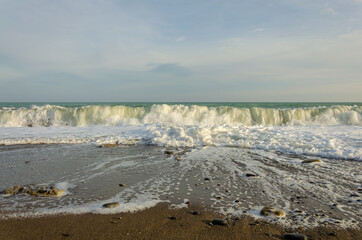 A sea wave running over a deserted sandy beach.