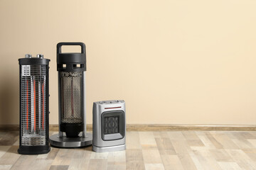 Different modern electric heaters on floor in room, space for text