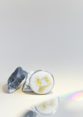 a brooch made of epoxy resin next to a marble stone on a beige background 