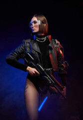 Fashionable woman with stylish haircut in black clothing poses holding a futuristic rifle....