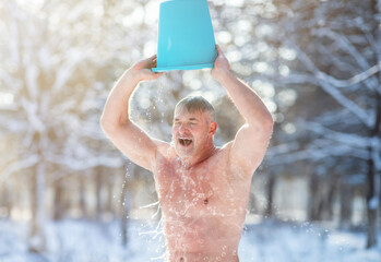 Senior man tempering his body, developing resistance to cold, pouring water onto himself outdoors...