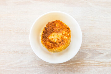 Homemade cottage cheese pancakes syrniki stack on round white bowl on white rustic table background