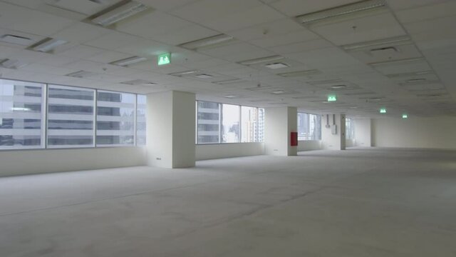 Handheld, camera moving backward &ndash; an unfurnished empty office space interior in a city high-rise after tenant move out. COVID-19 cause office space reduction. 