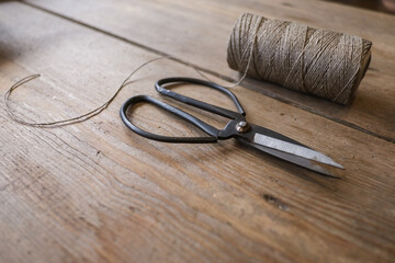 On a table are vintage scissors and a spool of thread