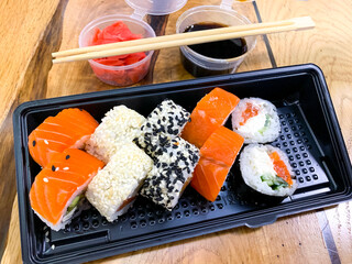 Set of rolls, ginger, soy sauce, sticks on wooden table.