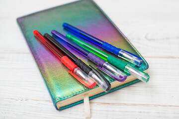 Multi-colored pens on a diary on a white wooden background. Planning, diary concept.