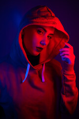 Portrait of a beautiful young woman in a sweatshirt with a hood in neon light