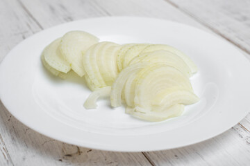 Chopped onion. On a plate on a white wooden background.