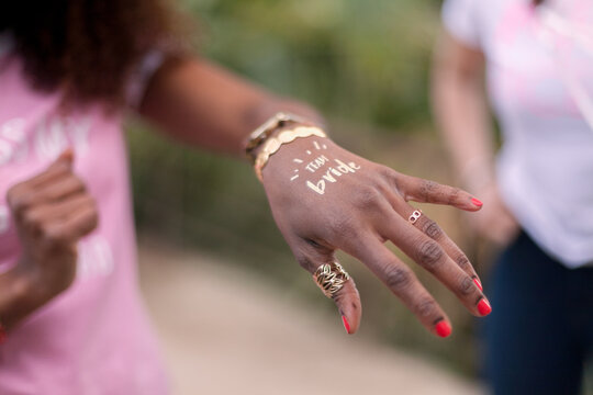Hand of beautiful African America girl with fake gold tattoo that says "Team Bride".