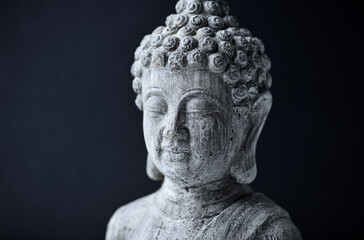 Meditating Buddha Statue on dark background. Close up. Copy space.
