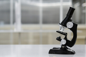 Microscope on white table on science laboratory background.