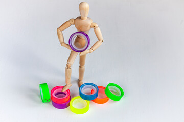 a wooden mannequin with a lot of colored scotch tape