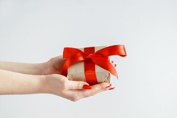 Gift with a red ribbon in hands on a white background