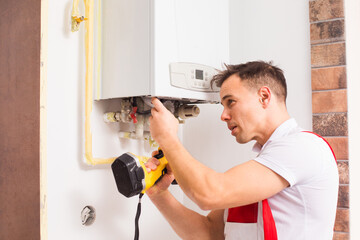 The plumber repairs a boiler at the kitchen