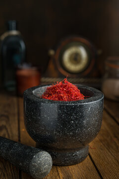 Saffron spices threads in dark granite mortar on dark table. Saffron flavor and coloring seasoning ingredient.