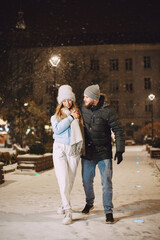 Winter holidays conception. Outdoor night portrait of young couple. Posing in street of European city.