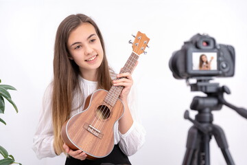 Young woman with guitar creating online content on white background with copy space