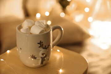 Obraz na płótnie Canvas Cup of hot drink with marshmallows on small wooden table, space for text. Christmas atmosphere