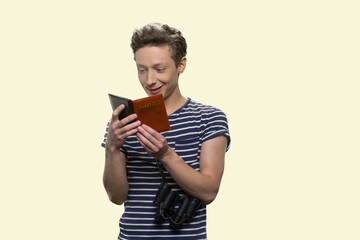 Teenage traveler with passport isolated on yellow background. Young cheerful boy with binoculars and documents.