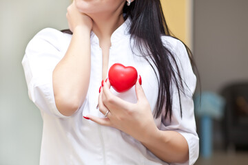 Woman in a medical uniform holding a heart in a hands.