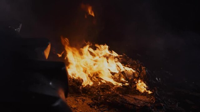 Campire on concrete. Fire burning on the ground, burning trash. Bonfire in the night.
