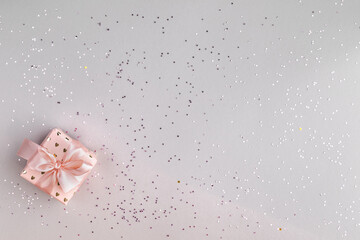 Festive pink box with a gift on a gray background. Top view, flat lay. Copy space. Birthday, mothers, valentines, women, wedding day concept.