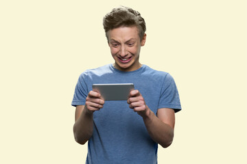 Unhappy boy is playing game in smartphone. Portrait of sad failed guy isolated on white background.
