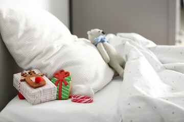 Fototapeta na wymiar Gift box with candy cane and gingerbread on bed in children's room. St. Nicholas Day tradition