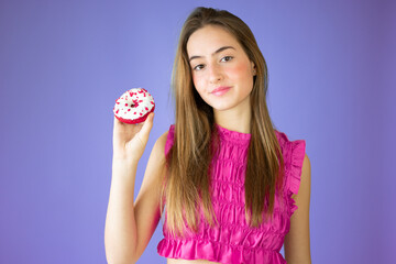 Beautiful girl holding donuts an having fun isolated over purple background. People with sweets.