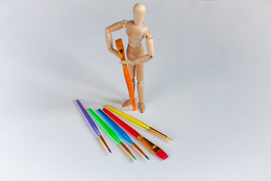 a wooden mannequin with a lot of bright colorful brushes