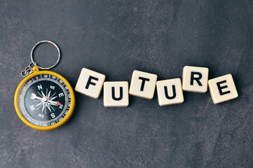 Top view of magnetic compass and scrabble letters with text FUTURE over black background. 