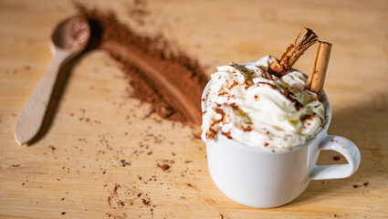 Primer plano de una taza de café con crema batida, cacao en polvo y canela