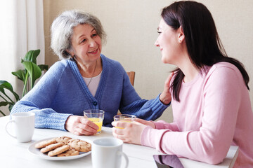 A daughter visits an elderly mother and they talk together at breakfast - A retiree woman is...